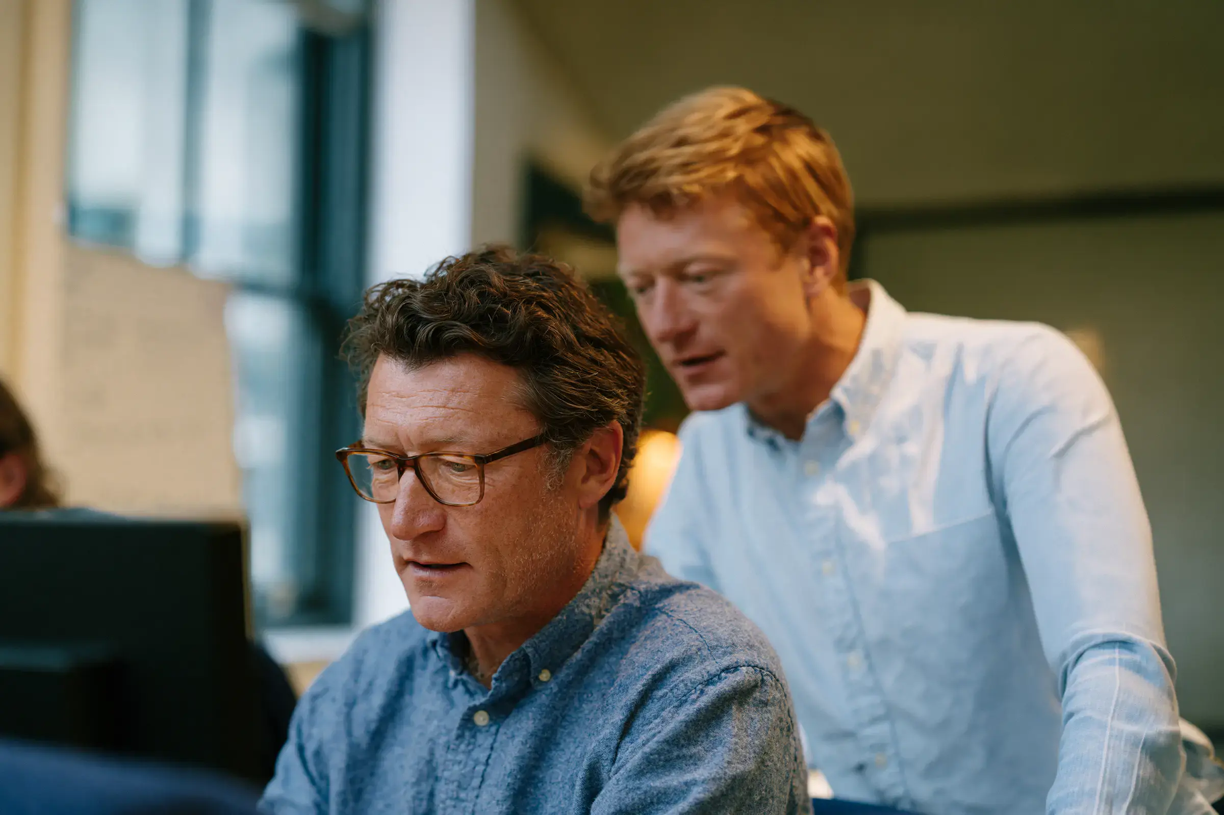 Two colleagues setting up a connector together at a computer